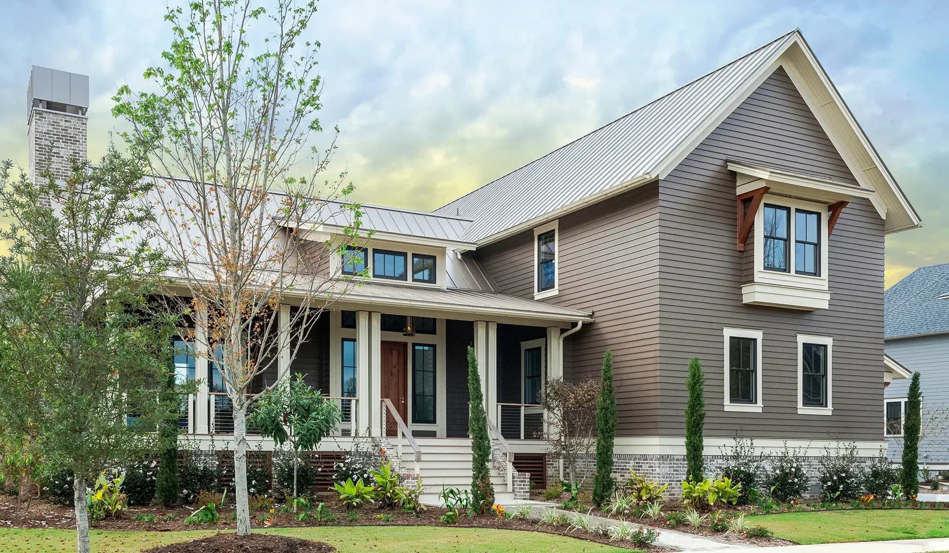A brown and white house with new James Hardie Lap siding and a standing seam metal roof.