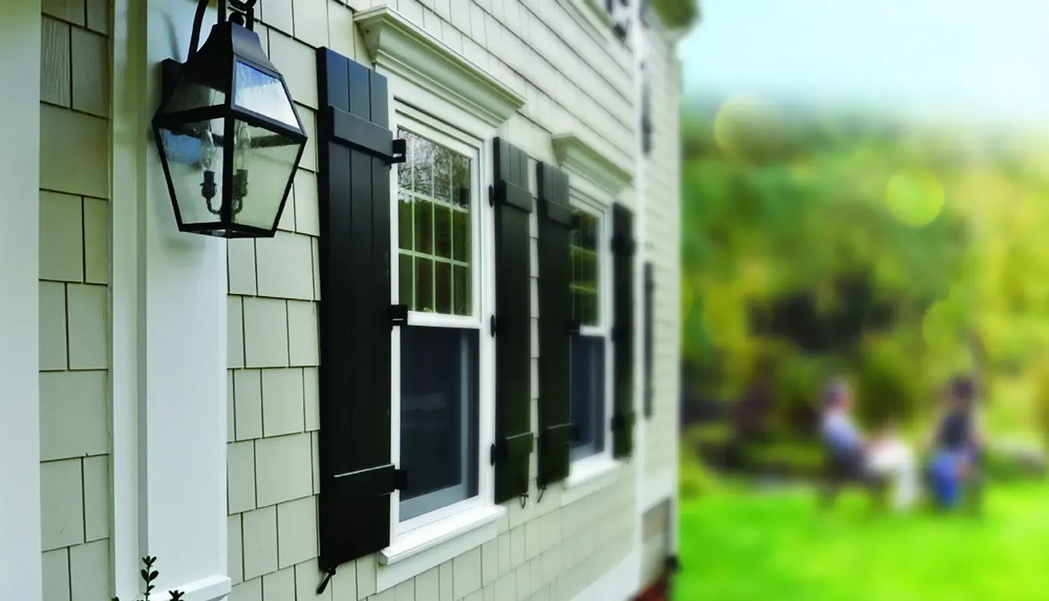 A gray house with black shutters and James Hardie shingle siding.